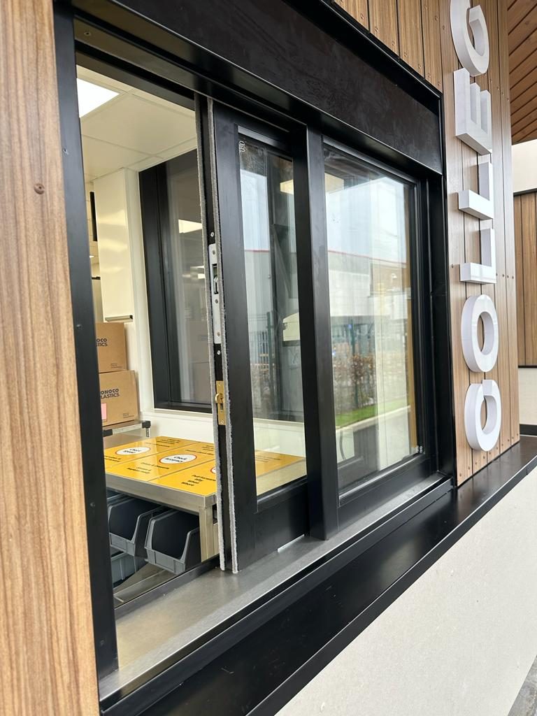 Sliding drive-thru service window in a timber-clad McDonald's booth at Knowsley