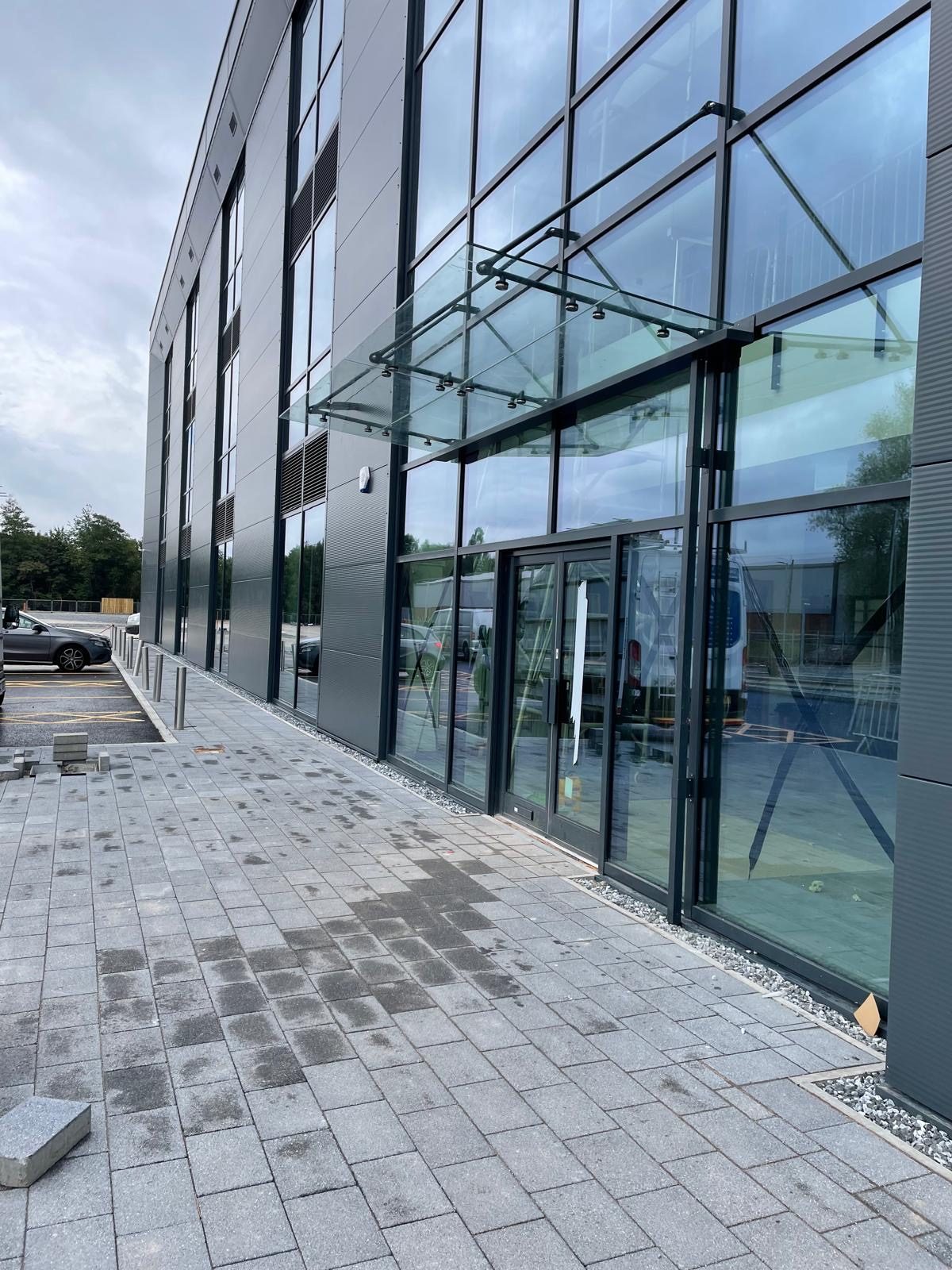Full-height aluminium glazing with double entrance doors and a glass canopy at Stakehill, Middleton