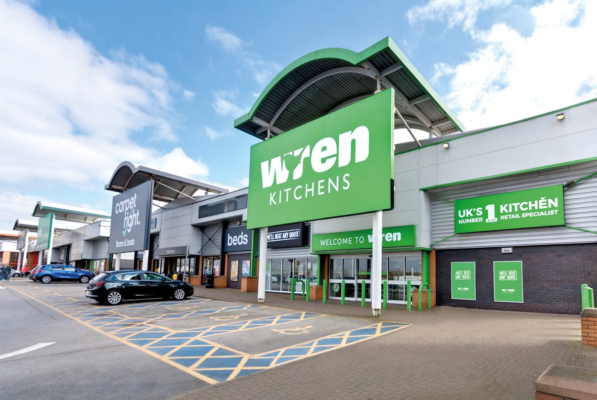 Wren Kitchens showroom in Ashton Under Lyne with a glazed frontage beneath a curved green fascia