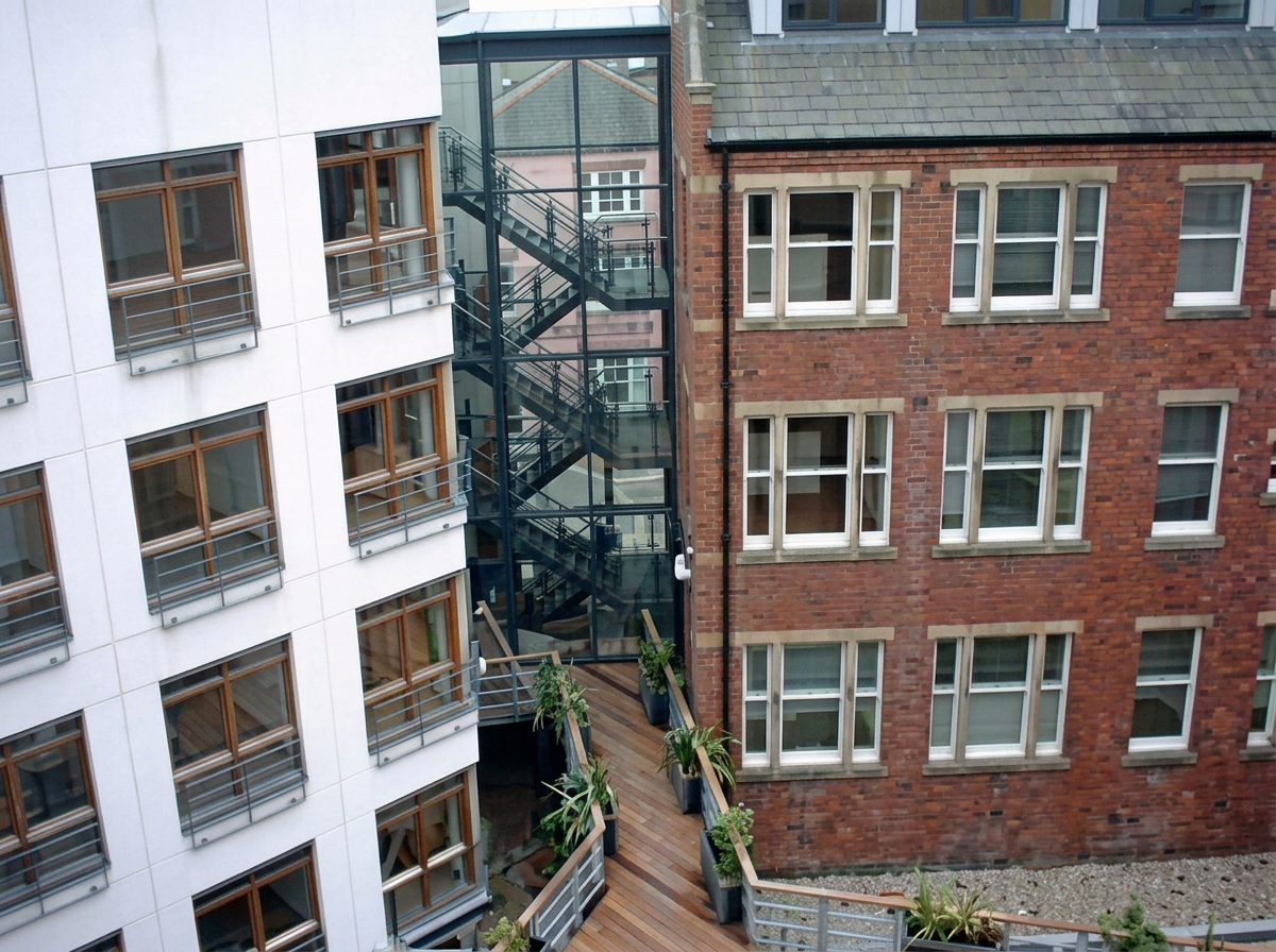 Modern building with glazed stair core beside a brick building on Dock Street, Leeds